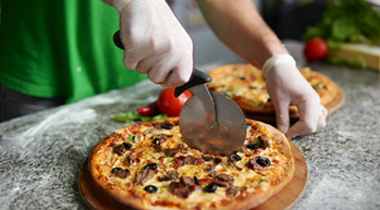 pizzaiolo entrain de couper une pizza